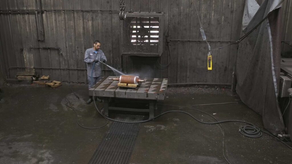 Repairman power washing a rotational motor part.